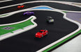 The Turbo Mini Drift Scene Remote Control Car Track by Lacatang Shop features toy cars racing through sharp curves for an exciting drifting experience. The vibrant track includes grass-like and water-like textures, with red, orange, purple, and gray cars speeding around a QR code on the ground.