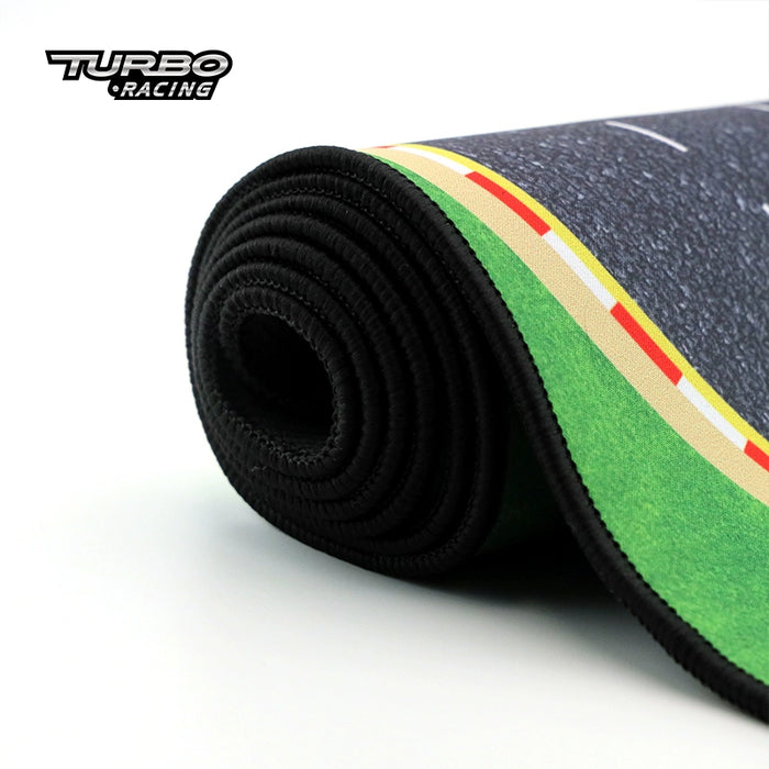 A close-up image of a racing track-themed gaming mat with a green grass edge and "Turbo Racing" in the upper left corner, ideal for Turbo Mini Drift Scene RC Race Car Track fans, by Lacatang Shop.