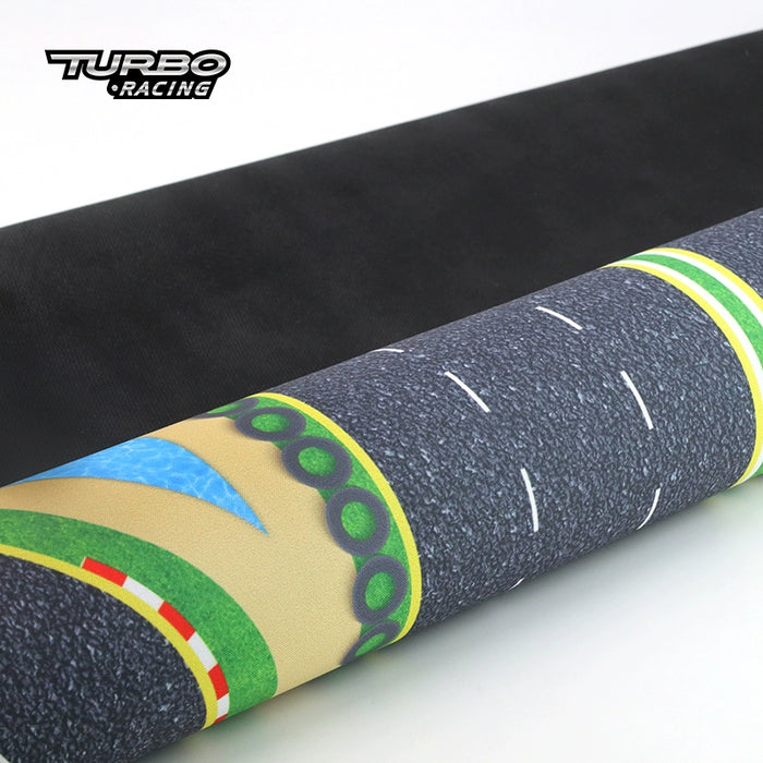 A close-up of a rolled racing track mat reveals detailed road markings and vibrant green borders with water patterns. The Lacatang Shop "Turbo Racing" logo in the top left promises an exhilarating drifting experience on your Turbo Drift Remote Control Car Track for Big and Small Scenes.