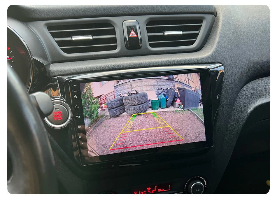 Lacatang Shop's Develuck HD 1080P 170° Fisheye Night Vision Car Rear View Camera, displayed on your car's dashboard, reveals a driveway with tire stacks and trash bins near a building. The waterproof AHD CVBS universal reverse lens provides night vision and visible guidelines.