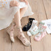 A person sits on a wooden floor wearing Lacatang Shop's delicate vintage floral lace ruffle socks. Nearby, four pairs of Kawaii Harajuku style crew socks in black, white, mint green, and pink are displayed. The look is completed with a white skirt adorned with orange polka dots.