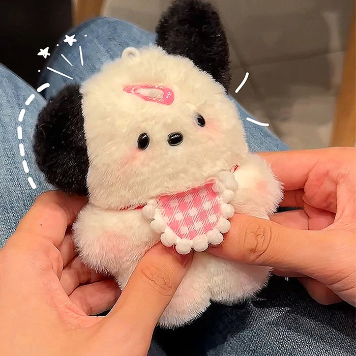 A person holds the Lacatang Shop's Adorable Plush Puppy Keychain, a cute cartoon bag charm for women and girls. This fluffy toy resembles a small white and black dog with a pink checkered bib and blushing cheeks. The background is slightly blurred, and the person wears blue jeans.