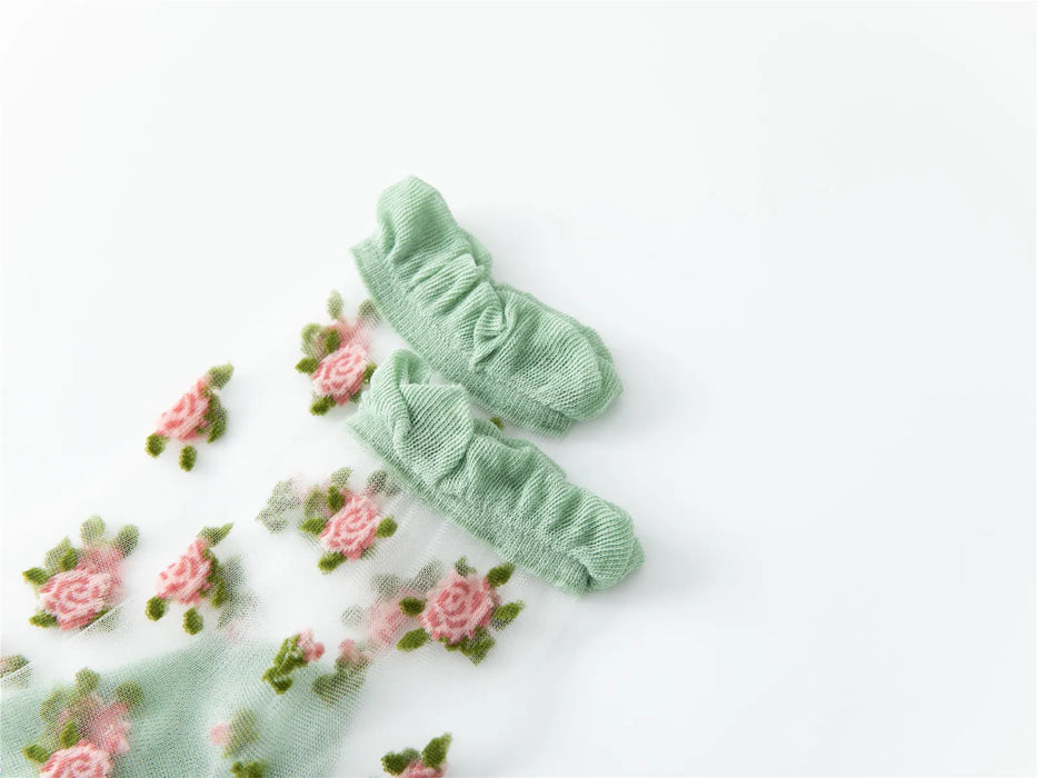 A close-up showcases the Delicate Vintage Floral Lace Ruffle Socks by Lacatang Shop, featuring pink rose embroidery and crystal silk. The kawaii Harajuku style integrates whimsical floral patterns, adding a feminine touch against a white background.