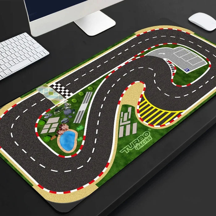 A desk displaying a keyboard and mouse on a Lacatang Shop's Portable Turbo Racing Rubber Mat, detailing winding tracks, a checkered finish, a pond, and greenery—ideal for thrilling 1:76 RC mini car races. Available in sizes 160x90cm & 180x80cm from Lacatang Shop.