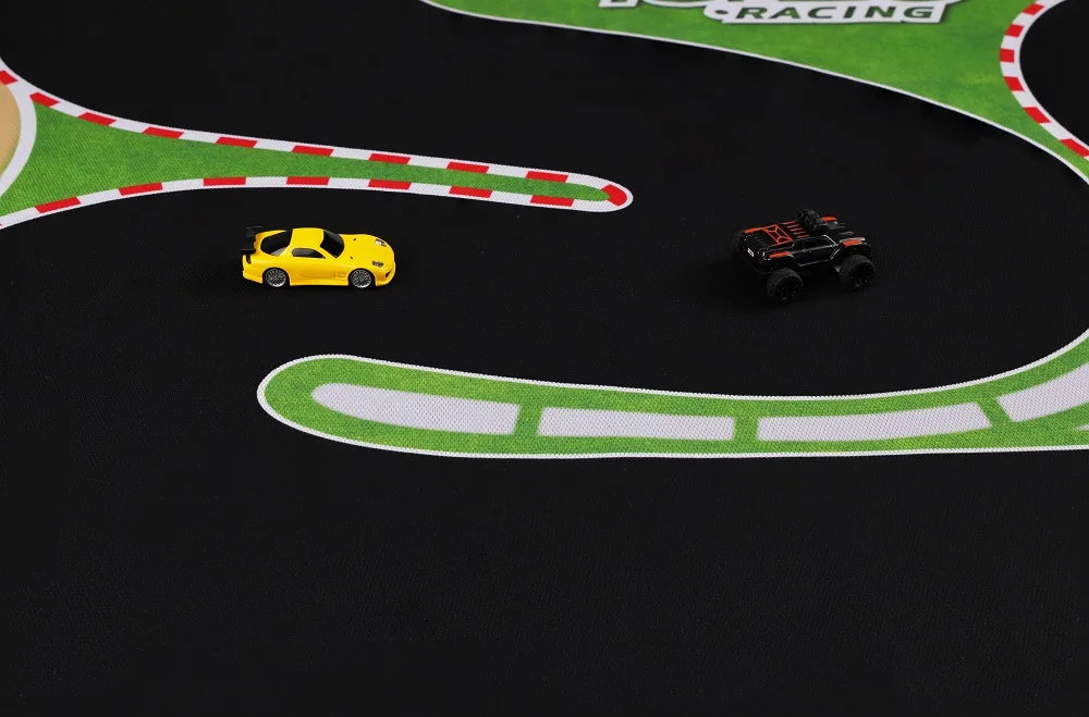 A yellow toy car and black truck sit on a Lacatang Shop Turbo Racing Rubber Track Mat, 1600x900mm, adorned with green and white patterns and red/white borders—perfect for 1:76 RC mini cars.