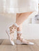 A person wears Lacatang Shop's Delicate Vintage Floral Lace Ruffle Socks with Crystal Silk, featuring pink flower designs and white cuffs, on a wooden floor. They pair these Kawaii Harajuku style crew socks with a white skirt, visible against a light background with a framed photo.