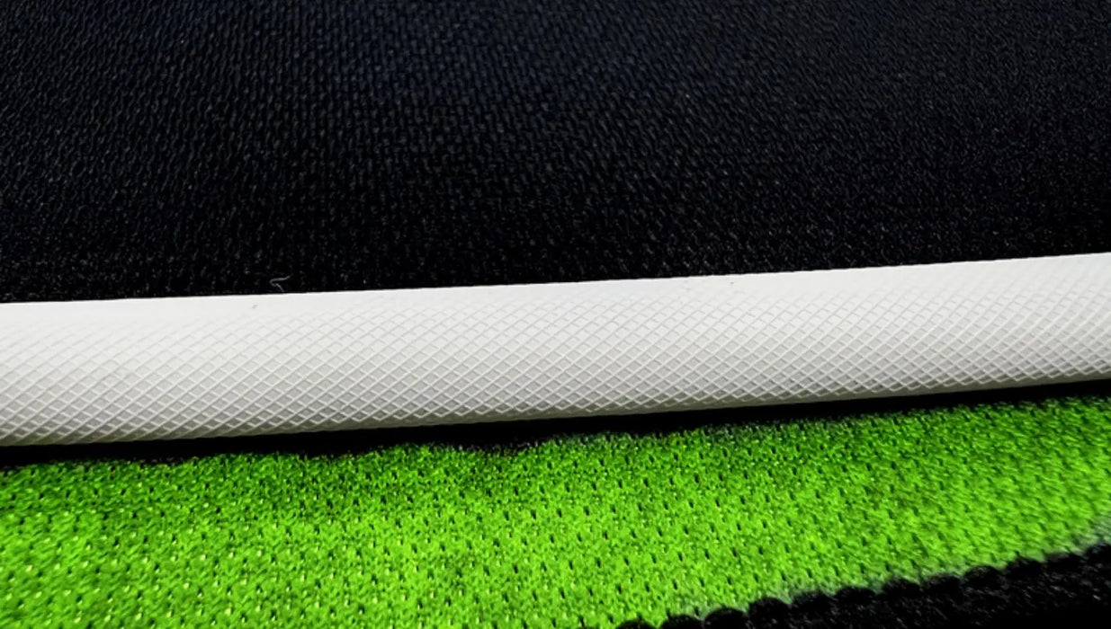 A close-up of a white textured cylinder, reminiscent of a component from Lacatang Shop's TURBO RACING 1:76 RC Car Racing Track Set with jump and drift features, placed diagonally on overlapping green and black textures, creates contrasts echoing a dynamic Turbo Racing scene.