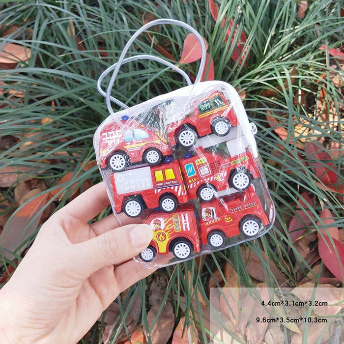 A hand holds a small transparent case with six red toy fire trucks, ideal for imaginative play by Lacatang Shop. In the background, green grass and scattered leaves set the scene. The case's dimensions are labeled in the bottom right corner.