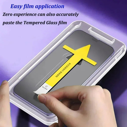 A person is holding a smartphone in a transparent plastic case, using a unique yellow arrow-shaped tool to assist in placing the AliExpress 1-2Pc 8K High End Tempered Glass for iPhone 15, 14, 13, 12, 11 Pro Max XS. The text reads, "Easy film application - Zero experience required to accurately apply the Tempered Glass film.