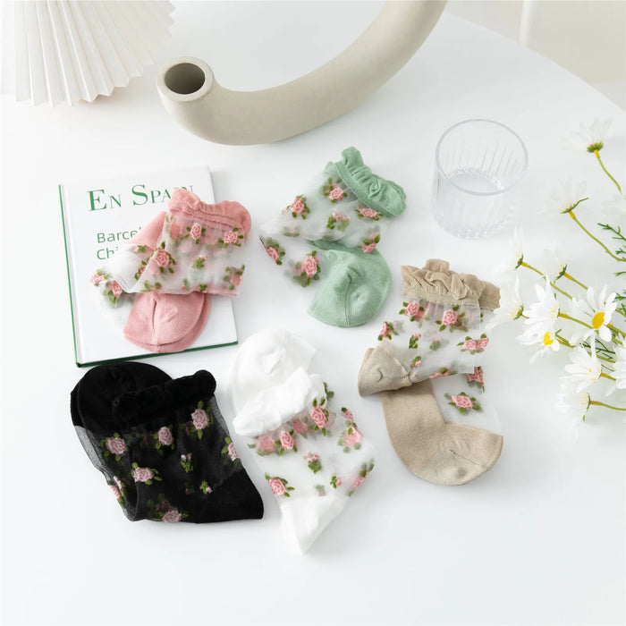 The Delicate Vintage Floral Lace Ruffle Socks by Lacatang Shop are artfully arranged on a white surface with a book, glass of water, and daisies, enhancing the kawaii Harajuku style ambiance.