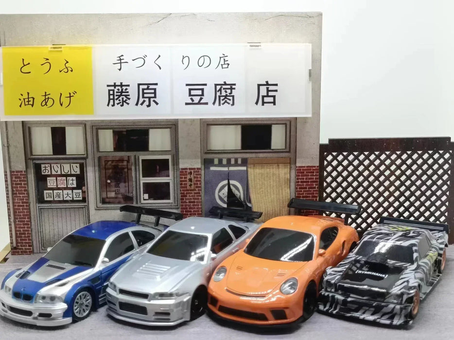 Four Lacatang Shop 2.4G RC Drift Cars are lined up in front of a diorama depicting a tofu shop. The cars, from left to right, are blue and white, silver, orange, and black with a white pattern. These high-speed remote control cars boast 4WD technology for unmatched performance. The shop features a white sign with Japanese text above the entrance.