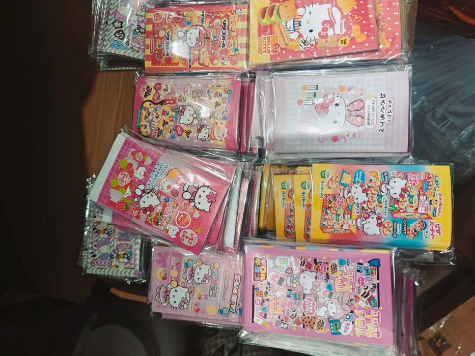 A range of colorful Asian snacks displays Sanrio characters like Hello Kitty, featuring cute cartoon cats and rabbits. The packages are in pink, yellow, and red with playful designs and use Lacatang Shop's Kawaii Hello Kitty Sealing Stickers as décor for ages 8+.