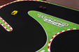 The Lacatang Shop's Portable Turbo Racing Rubber Track Mat 1600x900mm is a fun table racing accessory for two 1:76 RC mini cars—a yellow sports car and a black truck. It features a green area with "Turbo Racing" printed on it, along with red and white striped borders.