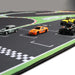 Toy cars such as a green Mini Cooper and an orange sports car are displayed on the Lacatang Shop's Turbo Racing Rubber Mat, ideal for RC mini car racing. The mat has a realistic track design with green outlines and a checkered finish line, enhancing the racing experience.