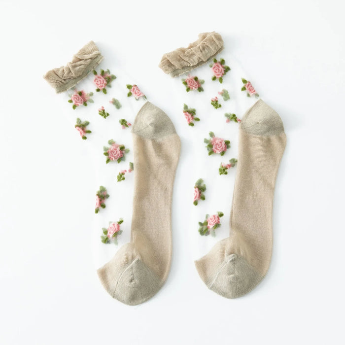 Lacatang Shop's Delicate Vintage Floral Lace Ruffle Socks feature a Harajuku-style with pink rose floral patterns, green leaves, and ruffled edges. Crystal silk adds charm while solid tan toe and heel sections contrast beautifully on a plain white background, adding whimsy to any outfit.