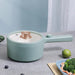 A pastel green 2024 New Portable 1.5L Multi-function Pot Rice Cooker from Lacatang Shop, featuring a lid and a long handle, is placed on a grey surface. Next to the pot is a light blue tray containing broccoli, shrimp, and other vegetables. A lime is also visible on the surface near the tray.