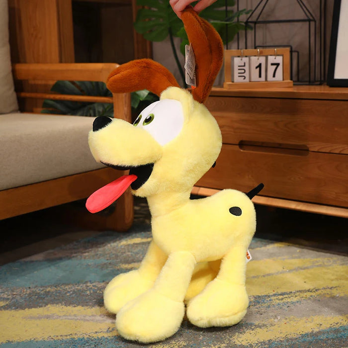 The Kawaii Oudi Dog plush toy by Lacatang Shop, featuring bright yellow fur, big green eyes, an open mouth with a red tongue, charming brown ears, and a quirky black spot on its back, sits perfectly on a blue and yellow rug among other plush toys. Perfect for room décor or as a Xmas gift.