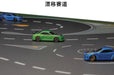 The TURBO RACING 1:76 Remote Control Car Racing Track Set by Lacatang Shop features three cars: a green car in the center, a blue car on the right, and another in the background. The track includes dashed white lines and arrows, with Japanese text displayed at the top.