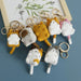 Lacatang Shop presents the Cute Cat Crochet Keychains Knitting Cartoon Cat Doll Keyrings For Car Keys. These kawaii small cat knitted keychains, available in charming colors such as yellow, gray, white, and pink, feature a handy loop for attaching to keys or bags. Displayed on a green surface with a framed picture above, they pair seamlessly with small cat earrings for an adorable look.