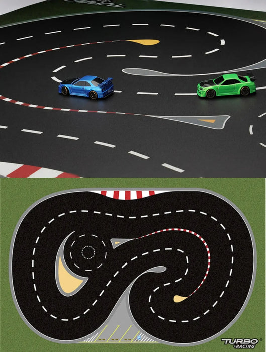 The Lacatang Shop's TURBO RACING 1:76 Scale Remote Control Car Track Kit features a customizable track with winding black roads, red/white barriers, drift jumps, and cement blocks. Two cars in blue and green race on the track below an illustrated map displaying the Turbo Racing logo.