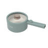 A teal-colored, round portable pot with a long handle is perfect for cooking. It features a transparent lid with a metallic knob on top and visible circular design patterns on the inner part of the lid. The brand name 