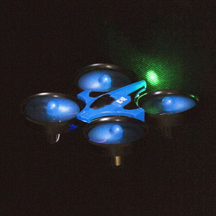 An Ivory Coeus Remote Control Mini Quadcopter, designed for both novice and advanced users with its easy-to-fly features and equipped with glowing green and blue LED lights, is hovering in mid-air against a dark background. The drone's four illuminated propellers create a vivid contrast with the darkness, offering a versatile flying experience.