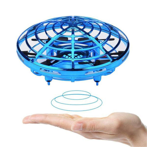 A blue, circular Jade Flying Helicopter Mini drone UFO RC Drone Infrared Induction Aircraft hovers above an outstretched hand, easily controlled by a beginner. The drone features a protective outer frame and lights underneath. Blue motion lines are drawn below the drone to emphasize its hovering effect. The wireless remote control provides seamless operation against the plain white background.